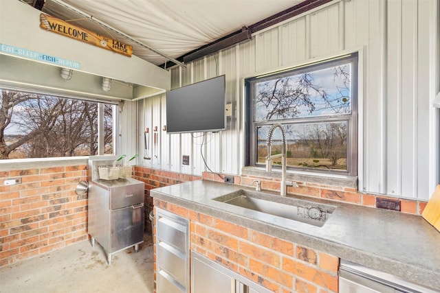 interior space with stainless steel dishwasher, sink, and concrete floors