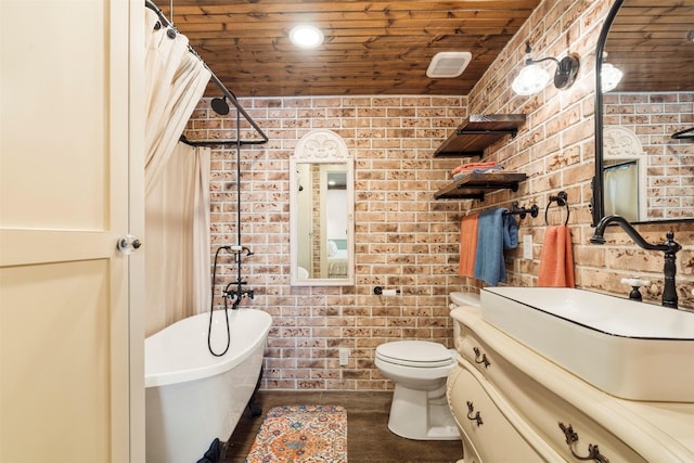 bathroom featuring toilet, vanity, a tub, brick wall, and wooden ceiling