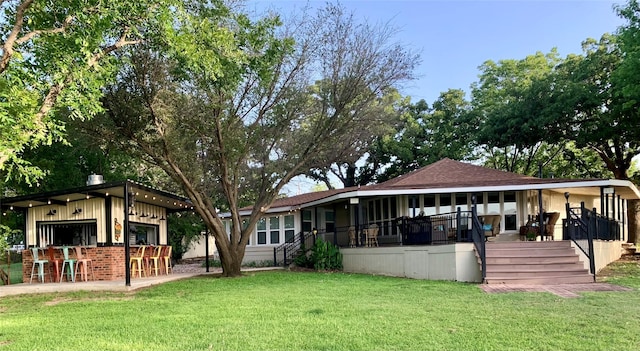 rear view of property with a lawn and outdoor dry bar