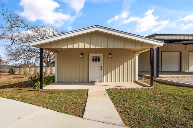 entrance to property featuring fence, a garage, and a yard