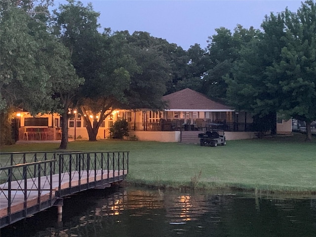view of dock featuring a lawn and a water view