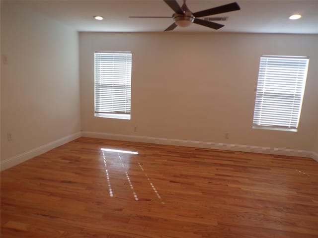 empty room featuring ceiling fan, wood-type flooring, and plenty of natural light