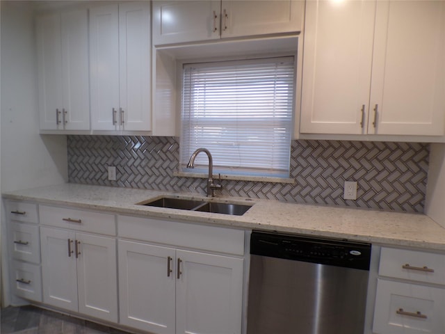 kitchen with tasteful backsplash, stainless steel dishwasher, white cabinets, light stone counters, and sink