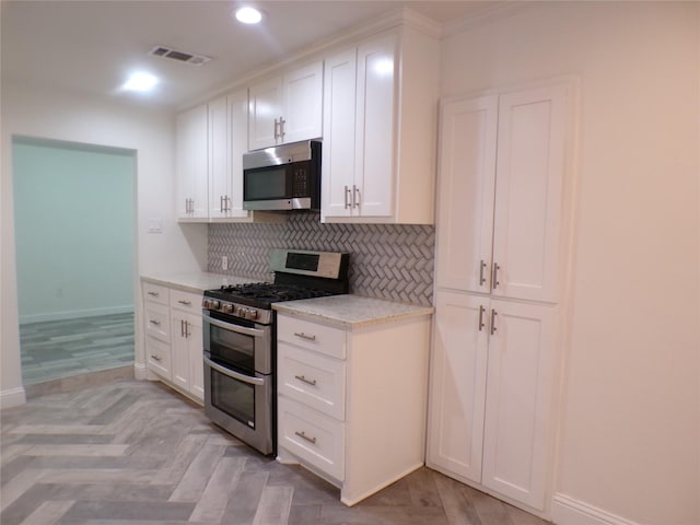 kitchen with light parquet flooring, white cabinetry, stainless steel appliances, and tasteful backsplash