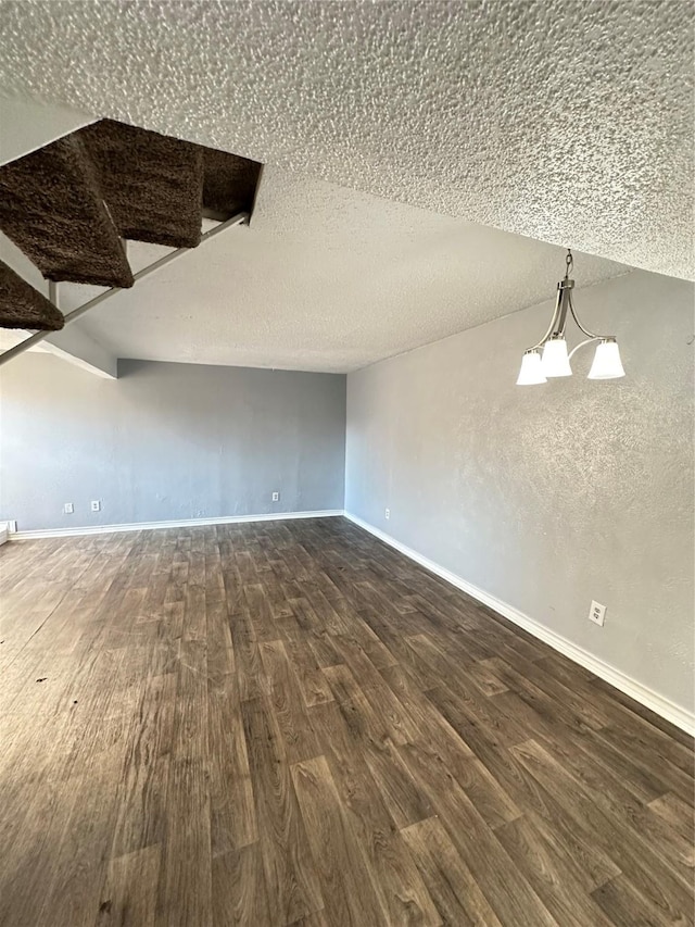 additional living space featuring a textured ceiling, dark hardwood / wood-style floors, lofted ceiling, and an inviting chandelier