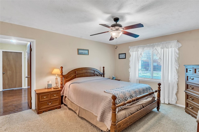 bedroom with a textured ceiling, ceiling fan, and light colored carpet