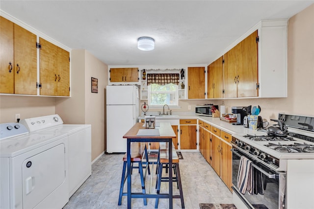 kitchen with white appliances, sink, and washing machine and clothes dryer