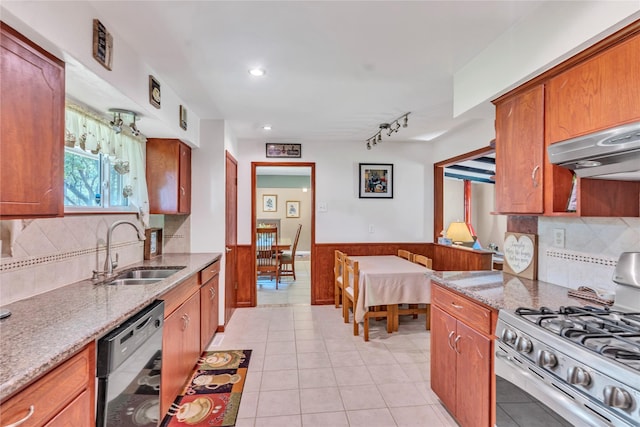 kitchen with light stone countertops, dishwasher, sink, rail lighting, and stainless steel range with gas stovetop