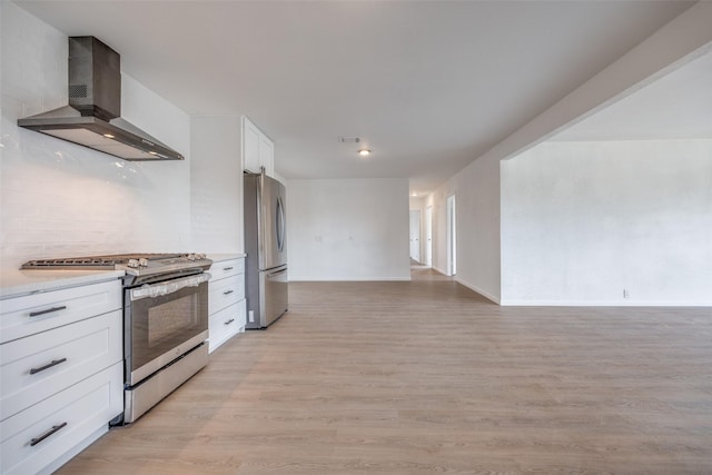 kitchen featuring white cabinetry, light hardwood / wood-style floors, stainless steel appliances, decorative backsplash, and wall chimney range hood