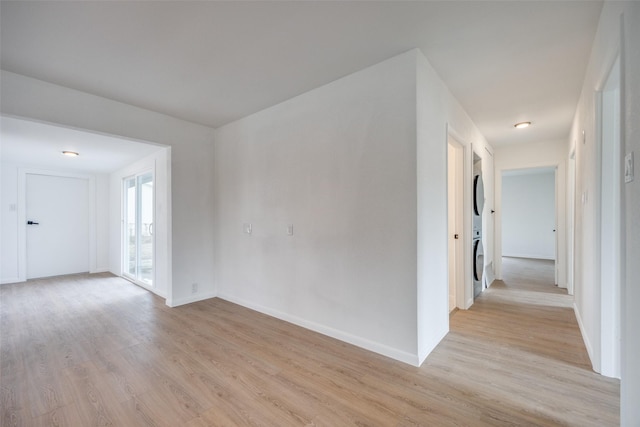 unfurnished room featuring stacked washing maching and dryer and light wood-type flooring