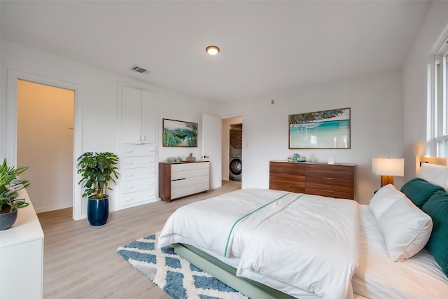 bedroom with washer / clothes dryer and light hardwood / wood-style floors