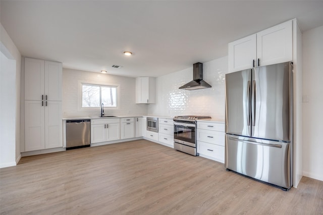 kitchen with white cabinets, appliances with stainless steel finishes, sink, and wall chimney exhaust hood