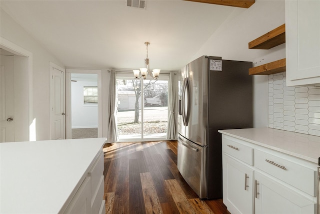 kitchen featuring white cabinetry, stainless steel refrigerator with ice dispenser, decorative backsplash, dark hardwood / wood-style flooring, and hanging light fixtures