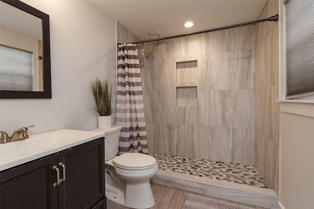 bathroom with toilet, a shower with curtain, hardwood / wood-style flooring, and vanity