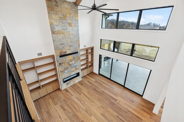 living room featuring ceiling fan, a high ceiling, and light hardwood / wood-style flooring