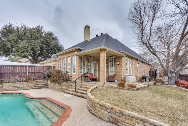 back of house featuring a fenced in pool, a lawn, and a patio