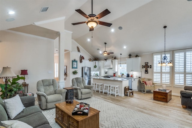 living room featuring lofted ceiling, light hardwood / wood-style floors, ceiling fan with notable chandelier, and plenty of natural light