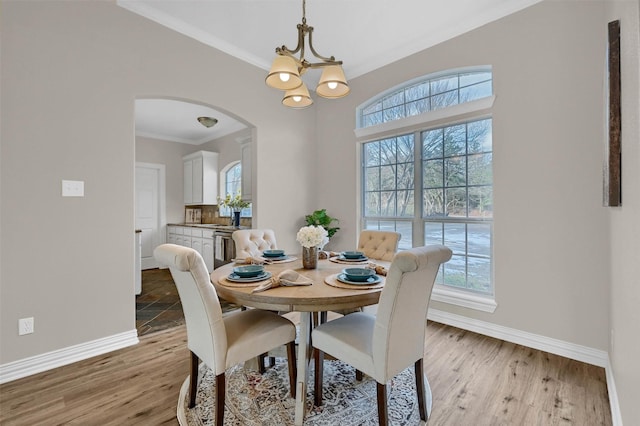 dining room with ornamental molding, a chandelier, and light hardwood / wood-style flooring