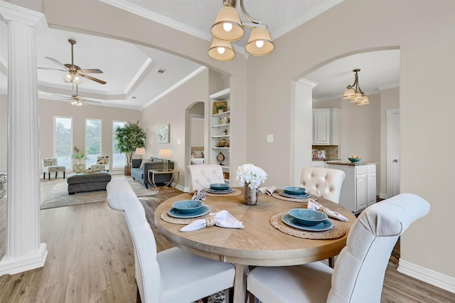 dining space featuring ornamental molding, ceiling fan, a raised ceiling, built in shelves, and light hardwood / wood-style flooring