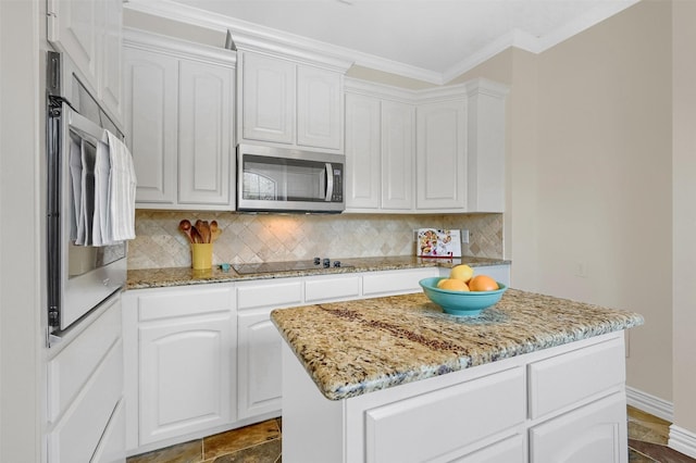 kitchen with white cabinetry, appliances with stainless steel finishes, a center island, and backsplash