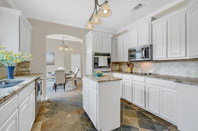 kitchen with appliances with stainless steel finishes, pendant lighting, white cabinetry, decorative backsplash, and light stone countertops