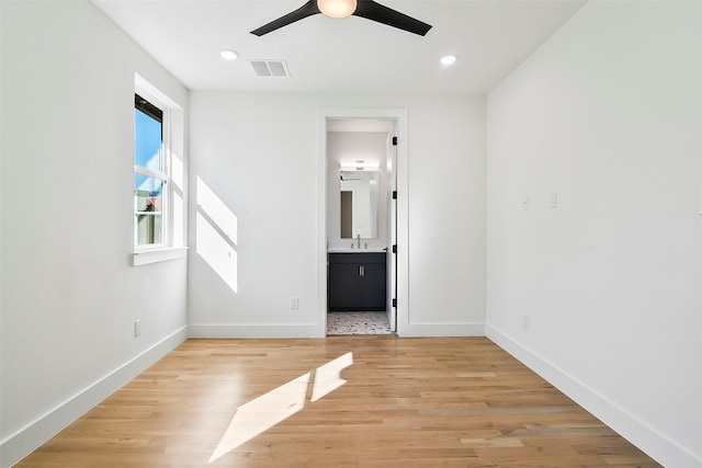 unfurnished bedroom featuring ceiling fan, sink, ensuite bathroom, and light hardwood / wood-style floors