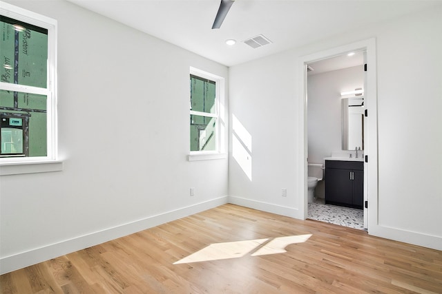 unfurnished bedroom featuring ceiling fan, sink, connected bathroom, and light hardwood / wood-style floors