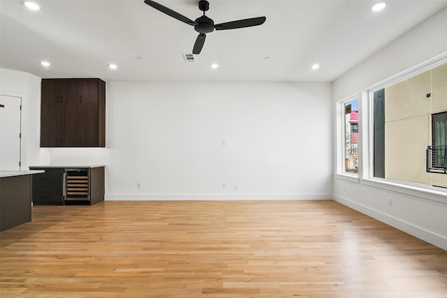 unfurnished living room with ceiling fan, light wood-type flooring, and beverage cooler