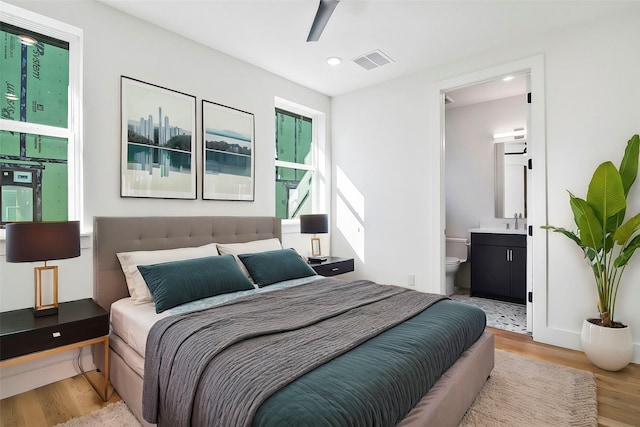 bedroom featuring ensuite bath, ceiling fan, sink, and light hardwood / wood-style floors