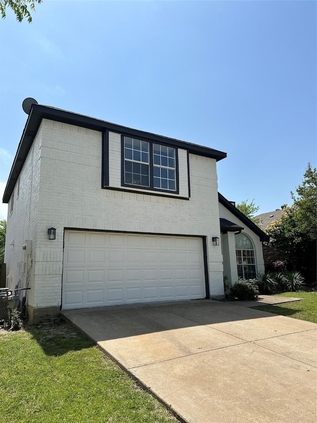 view of side of property with brick siding, a garage, and driveway