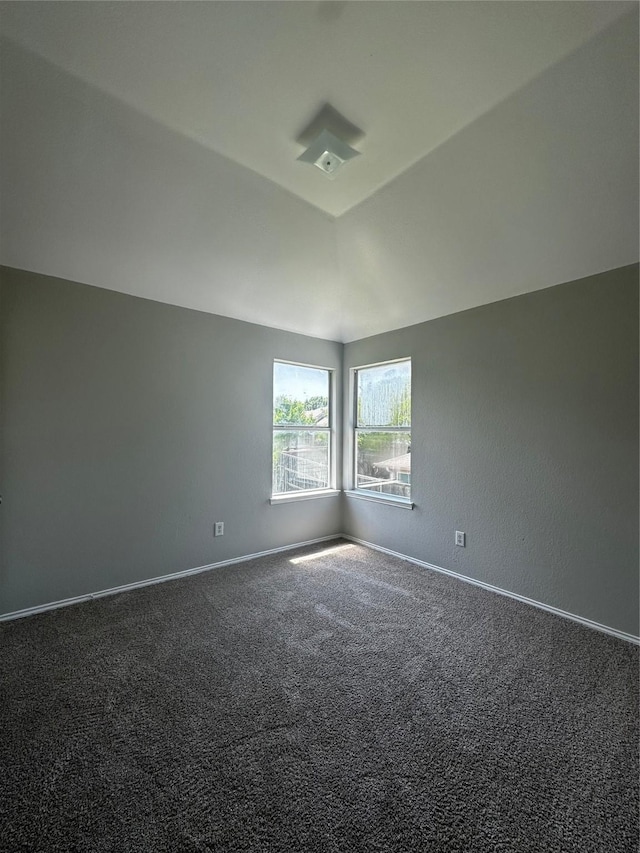 empty room featuring carpet, baseboards, and vaulted ceiling