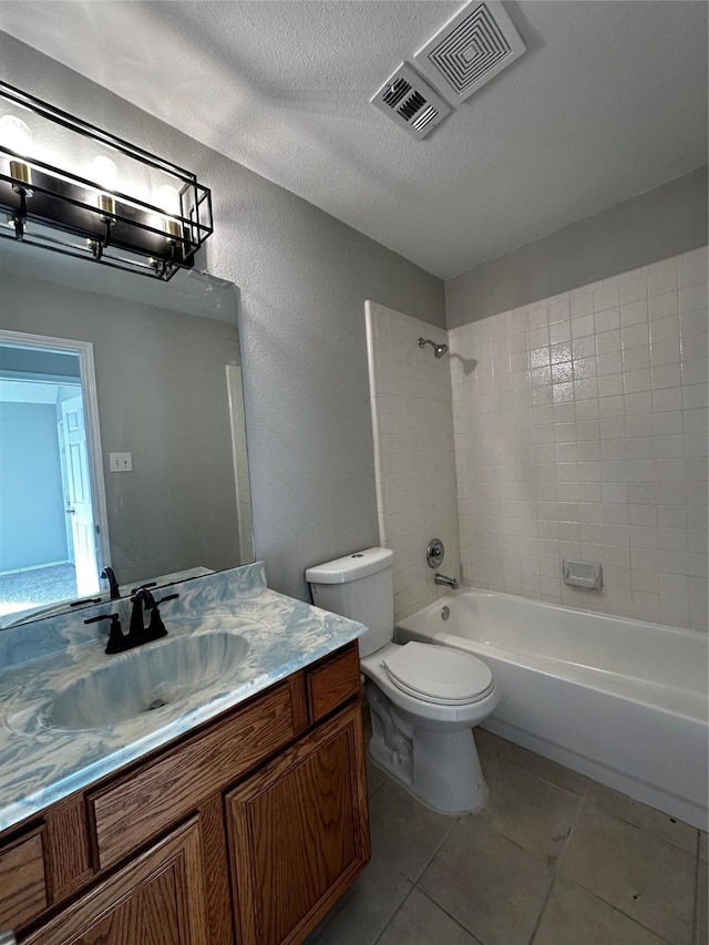 full bathroom featuring toilet, tiled shower / bath, tile patterned flooring, vanity, and a textured ceiling