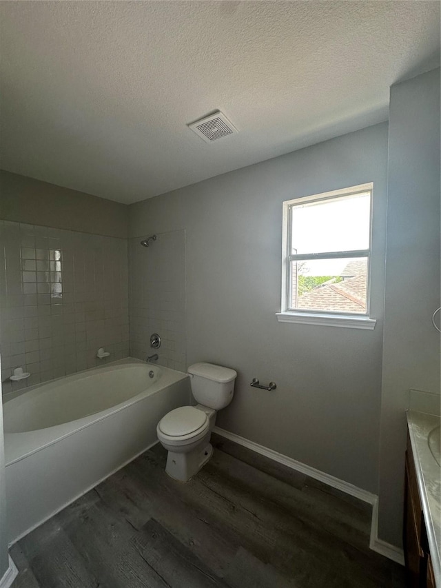 bathroom with wood finished floors, toilet, a textured ceiling, shower / bath combination, and vanity