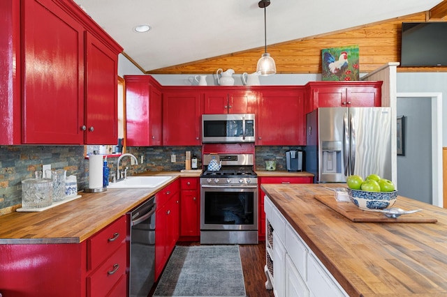 kitchen with pendant lighting, lofted ceiling, butcher block counters, stainless steel appliances, and backsplash