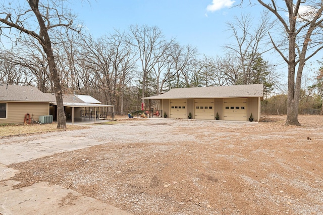 exterior space with a garage, central AC unit, an outdoor structure, and a carport