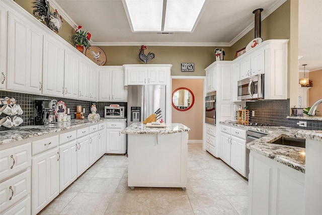 kitchen with backsplash, a kitchen island, white cabinetry, stainless steel appliances, and light stone counters