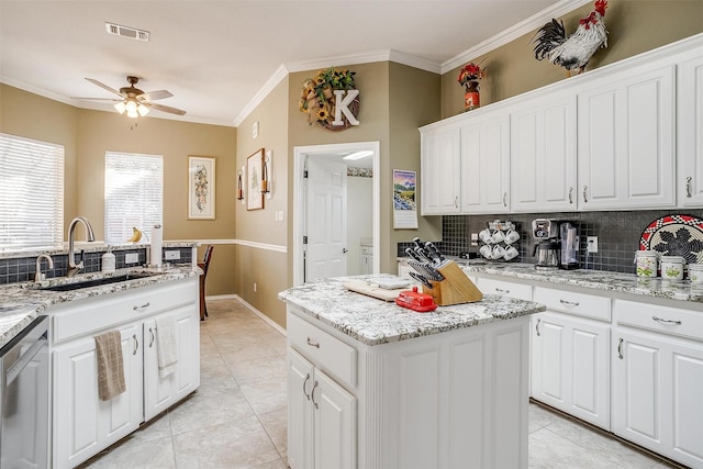 kitchen with stainless steel dishwasher, sink, white cabinetry, and a kitchen island