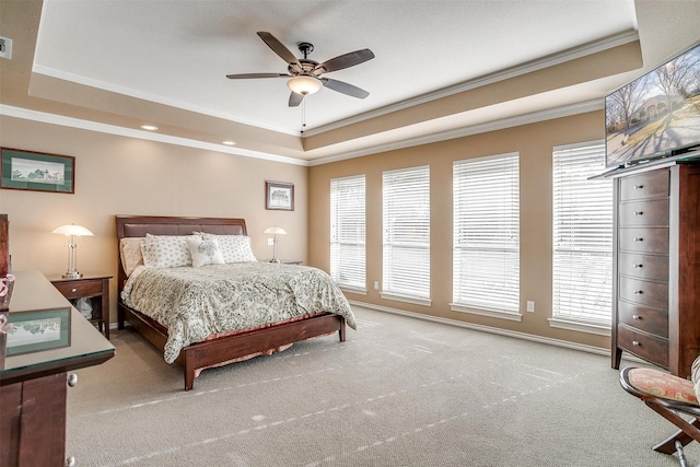 carpeted bedroom with ceiling fan, multiple windows, a tray ceiling, and ornamental molding