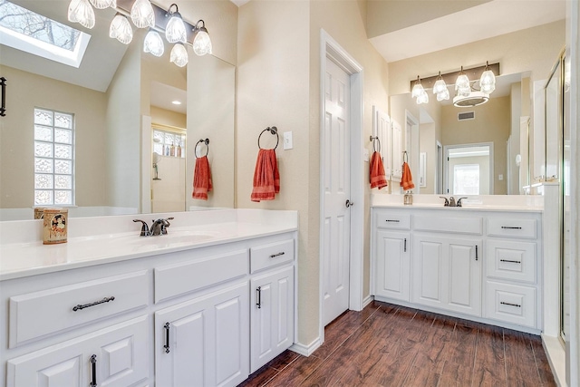 bathroom featuring vaulted ceiling with skylight, hardwood / wood-style flooring, and vanity