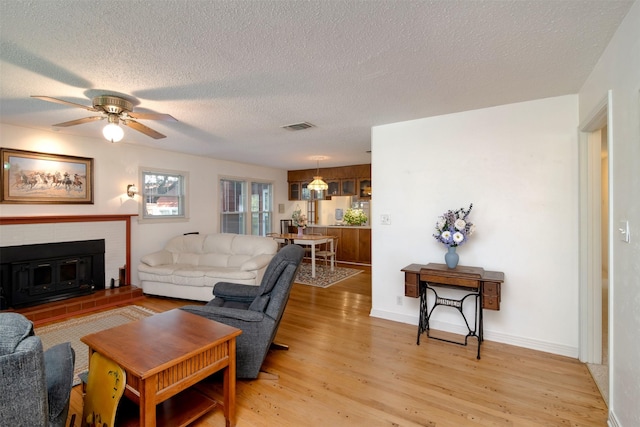 living room featuring ceiling fan, a textured ceiling, and light hardwood / wood-style flooring