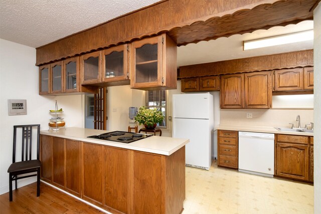 kitchen with sink, white appliances, kitchen peninsula, and a textured ceiling