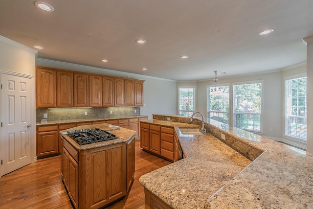 kitchen with decorative light fixtures, sink, gas stovetop, and a large island