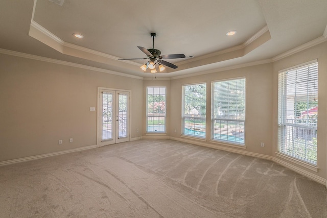 carpeted spare room featuring a raised ceiling, ceiling fan, french doors, and crown molding