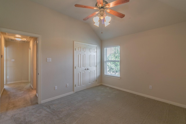 unfurnished bedroom featuring light carpet, vaulted ceiling, a closet, and ceiling fan