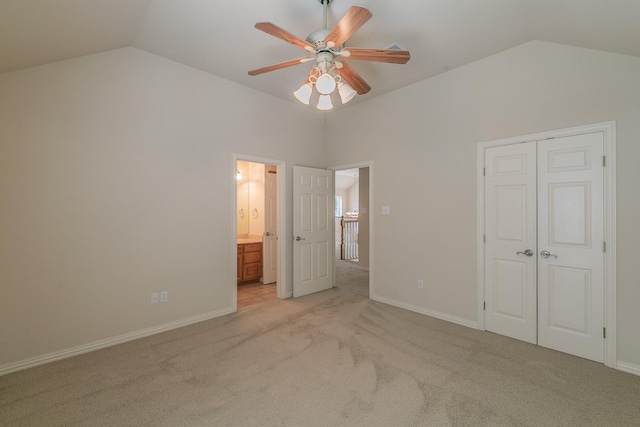 unfurnished bedroom with ensuite bath, lofted ceiling, a closet, ceiling fan, and light colored carpet