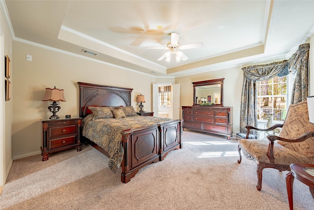 carpeted bedroom with ceiling fan, a tray ceiling, and multiple windows