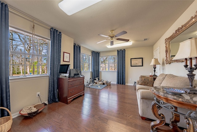 living room with ceiling fan, a wealth of natural light, dark hardwood / wood-style floors, and a textured ceiling