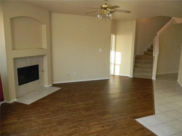 unfurnished living room with ceiling fan and a tiled fireplace