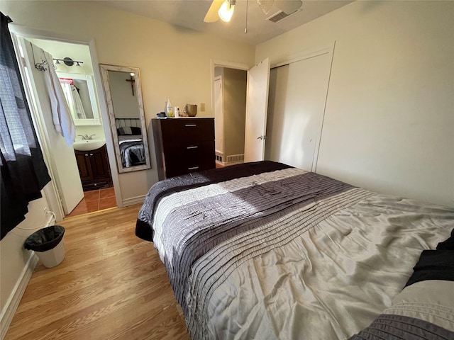 bedroom with ensuite bath, sink, a closet, light wood-type flooring, and ceiling fan