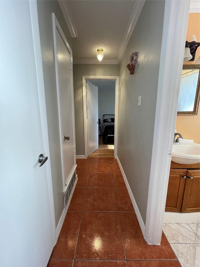 corridor featuring sink, dark tile patterned floors, and crown molding